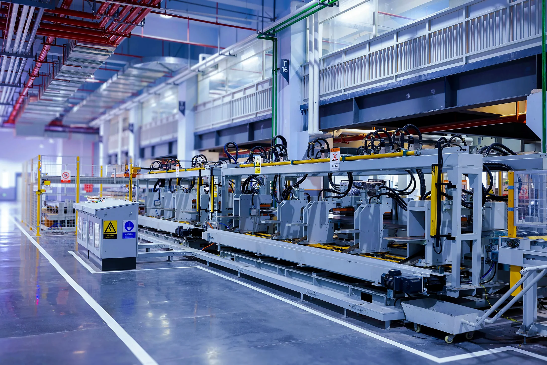Industrial production line with metal-framed equipment and a control cabinet.