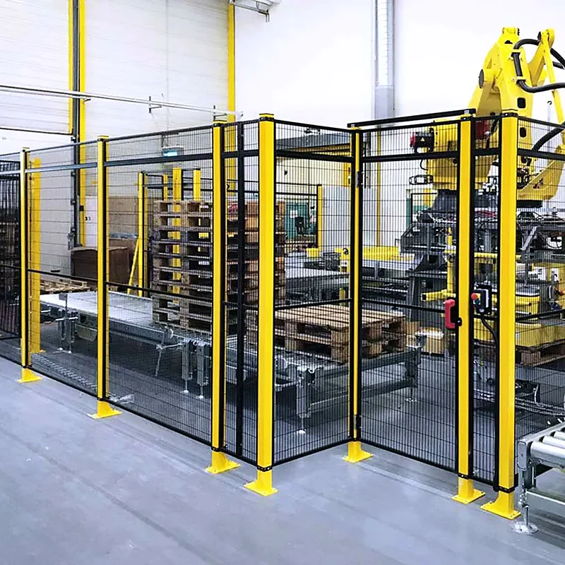 Yellow industrial robot and pallets behind black mesh fencing with yellow posts.
